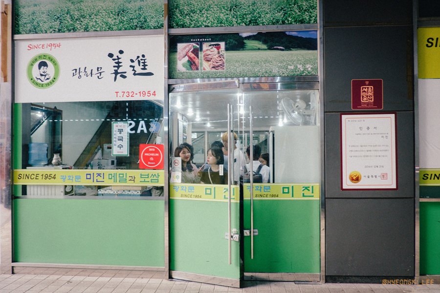 Storefront of Gwanghwamun Mijin, with "SINCE 1954" printed above the restaurant's name in Korean and a Michelin star sticker on the glass door