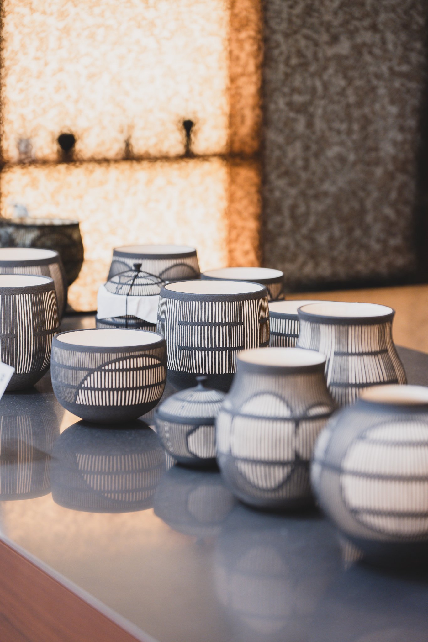 A cluster of striped ceramic cups and vases from Les loisirs, arranged on a display table