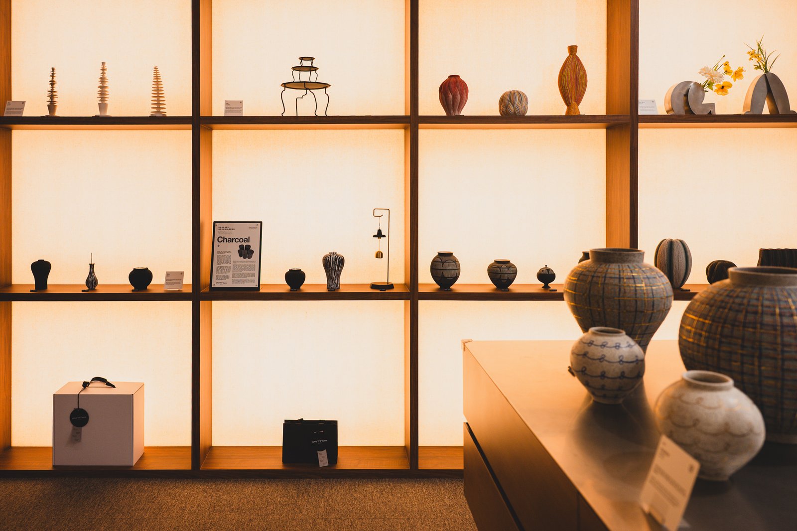A warmly lit display shelf showing the range of ceramic work carried at Hand to Home