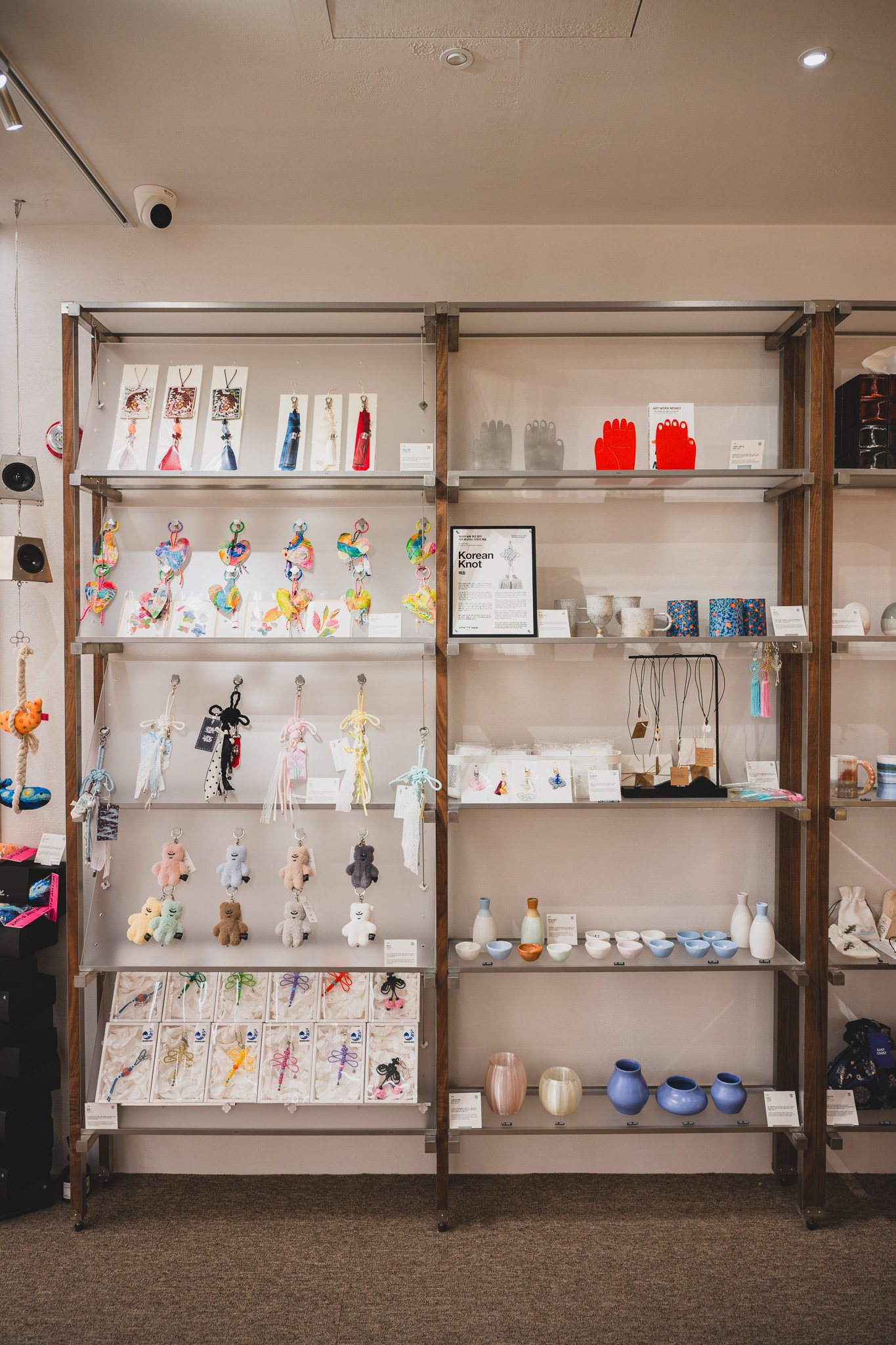 One wall of Hand to Home's shelving, mixing keychains, knot charms, jewelry, and small ceramics from dozens of makers