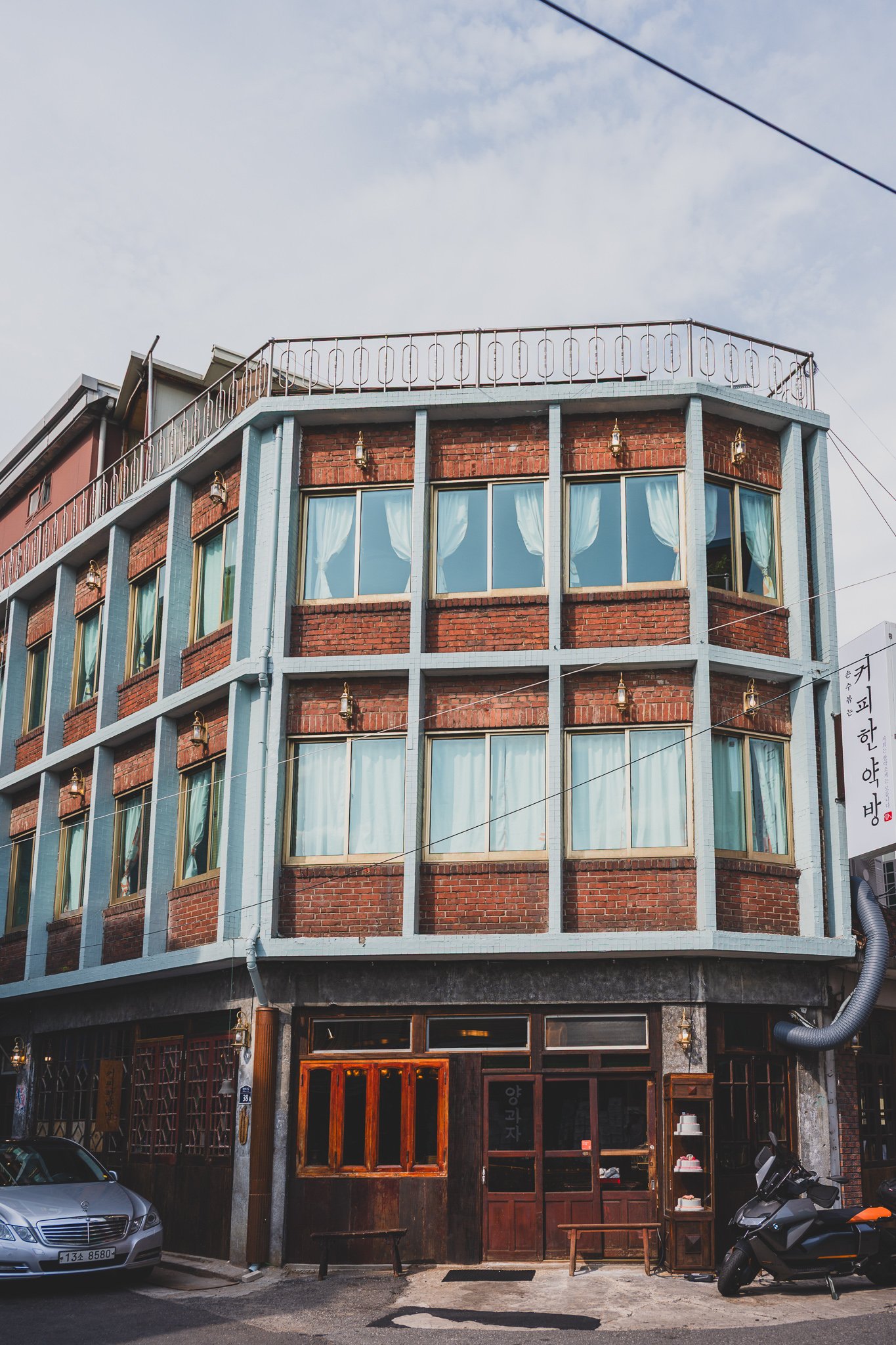 Exterior of the Gyeongdong Market branch, a three-story corner building with red brick and mint-green trim, standing out among the market's storefronts
