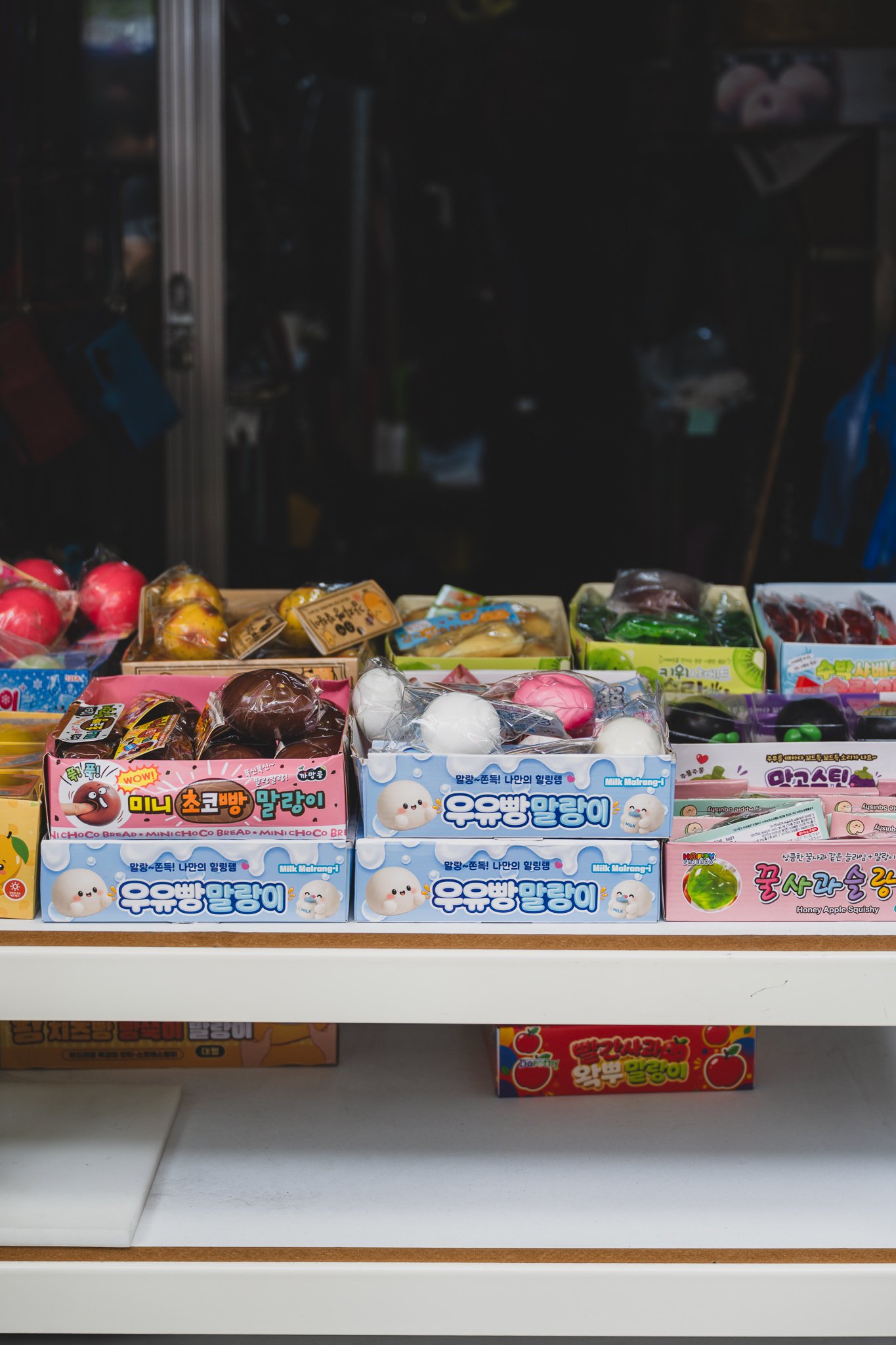 A street stall stacked with boxes of character-shaped slimes and squishy toys, like milk-bread and mini chocolate-bread designs