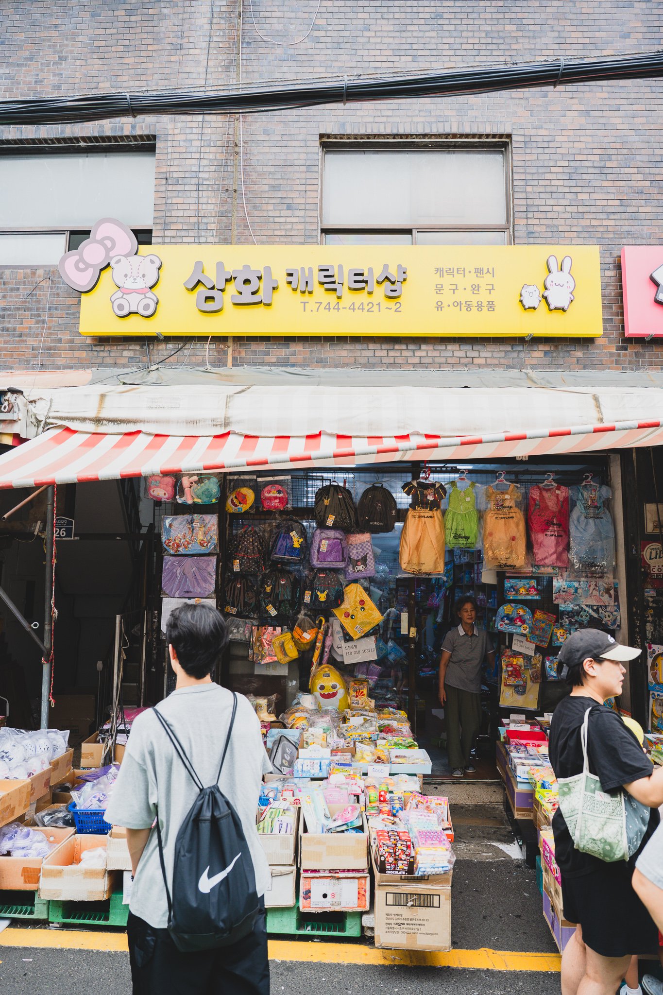 Yellow "Samhwa Character Shop" signage, specializing in character stationery, toys, and baby/kids goods
