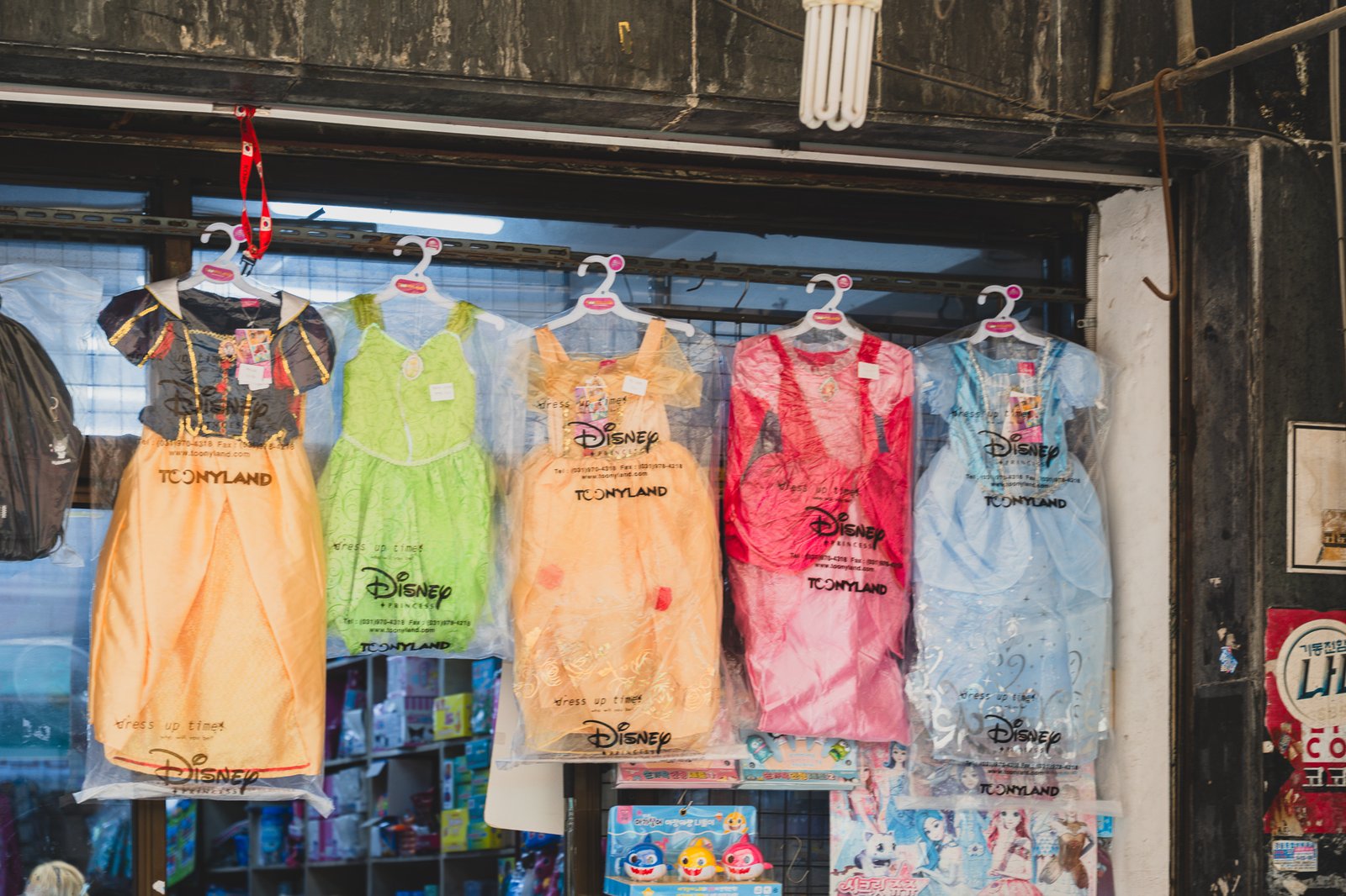 Five Disney princess dresses — Tony Land brand — hanging in a row, each a different color