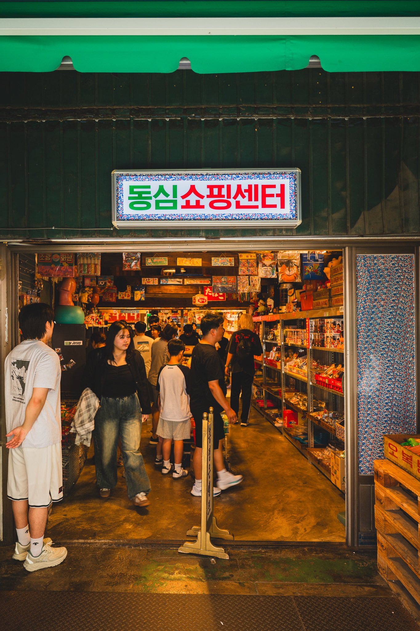 Entrance to "Dongsim Shopping Center," people walking in through a narrow storefront