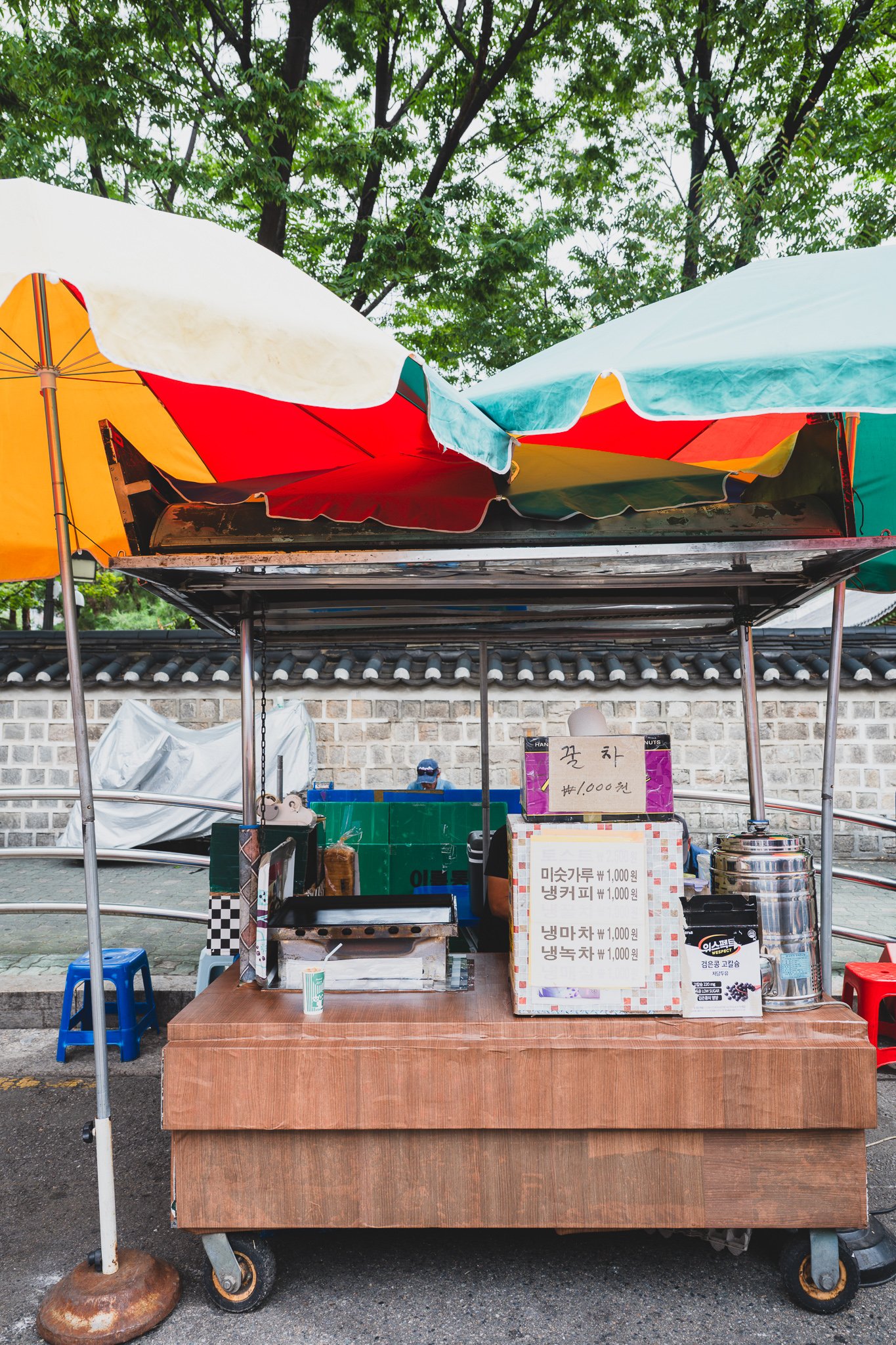 A street food stall's price board listing misutgaru and other drinks at a flat 1,000 won