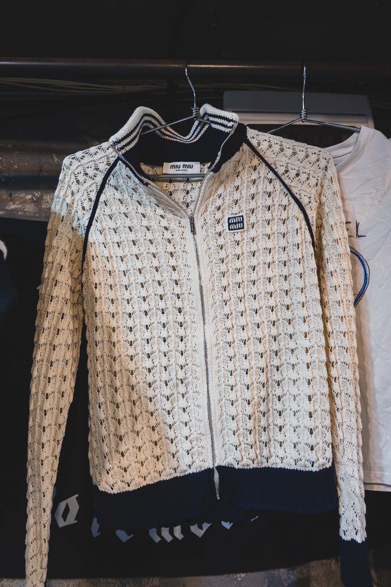A Miu Miu crochet-knit zip jacket on a hanger at one of the high-end vintage stalls