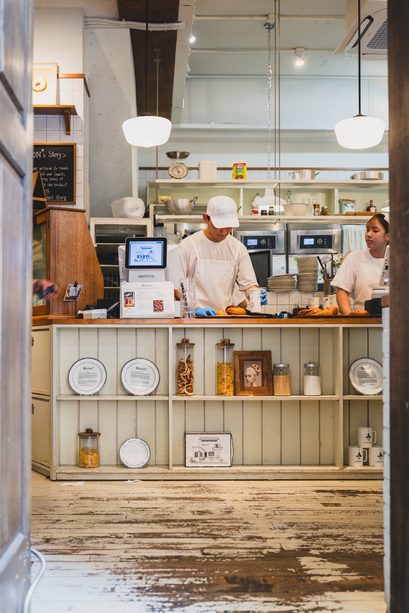 Interior of BETON showing the counter and open kitchen just past the entrance, with pendant lighting and worn wood floors