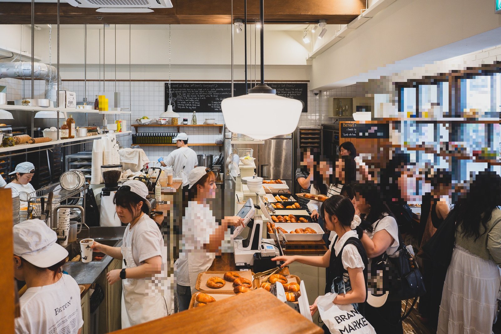 The busy ground-floor counter at peak time, staff plating salt bread onto wooden trays while customers line up to order