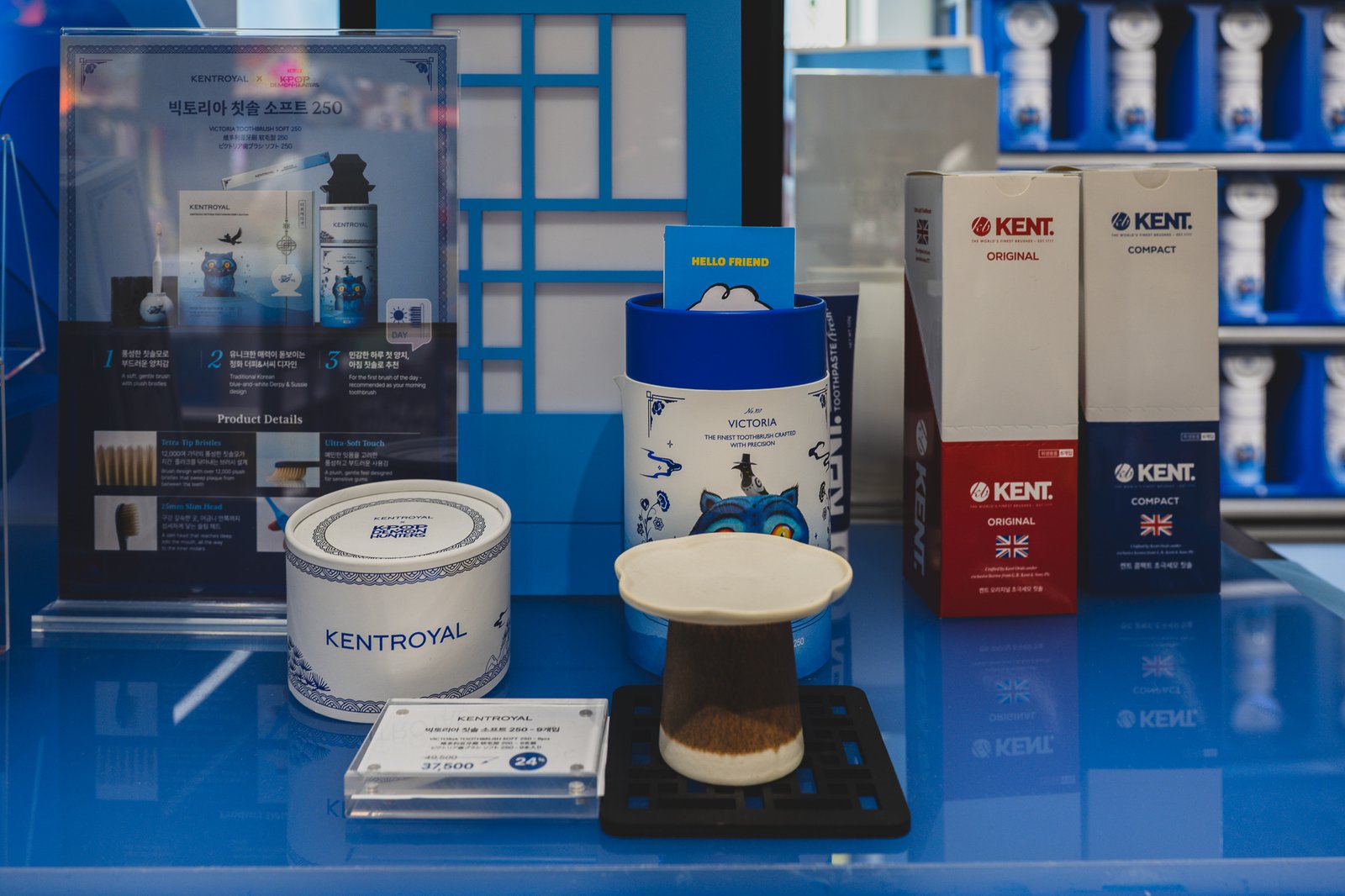 Display table with the Victoria toothbrush gift set arranged next to the KENT Original and Compact boxes, shown side by side rather than pushing only the collab items