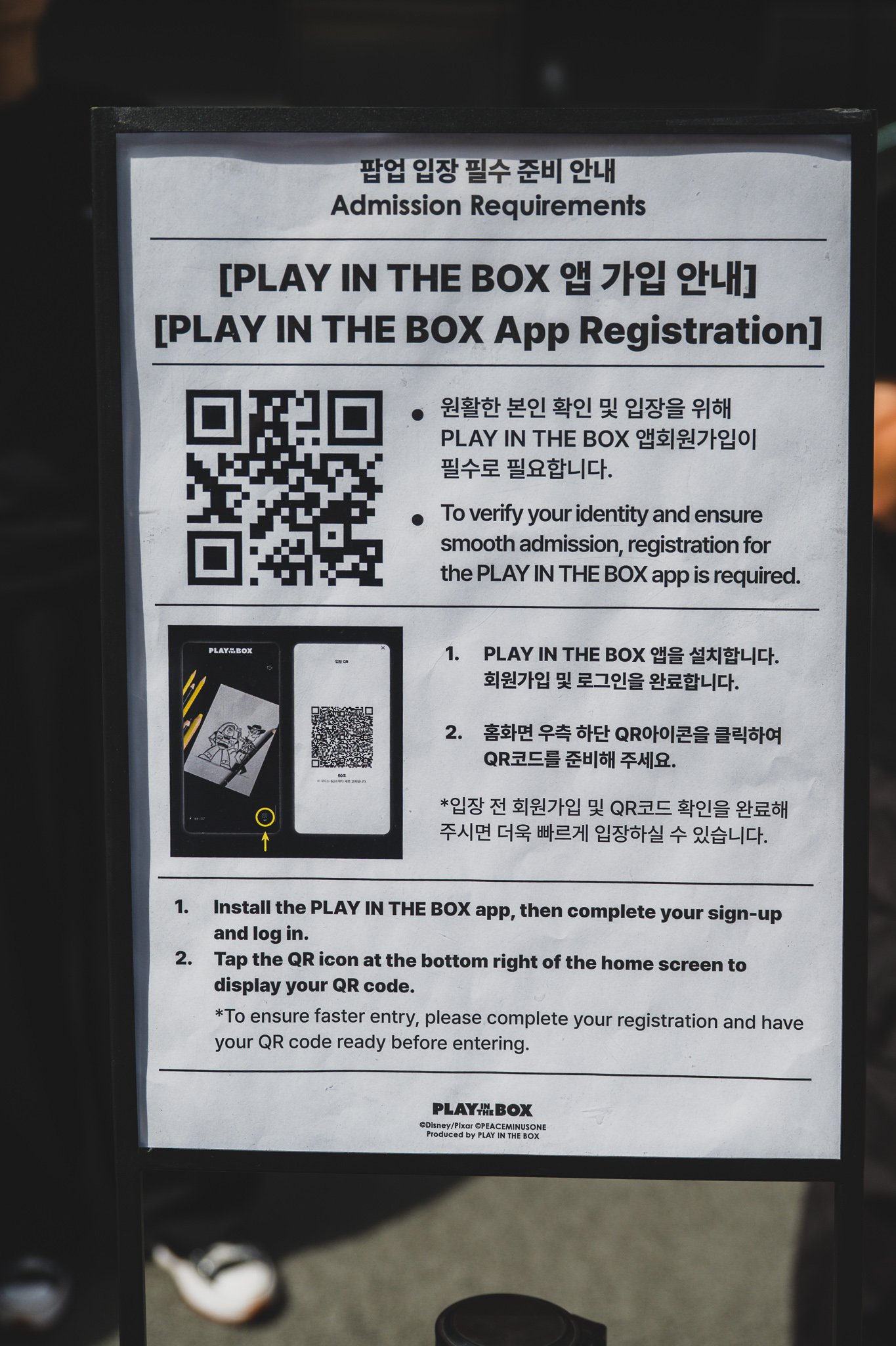 The "Admission Requirements" signage at the entrance, showing a QR code and step-by-step instructions in Korean and English for installing the PLAY IN THE BOX app before entry