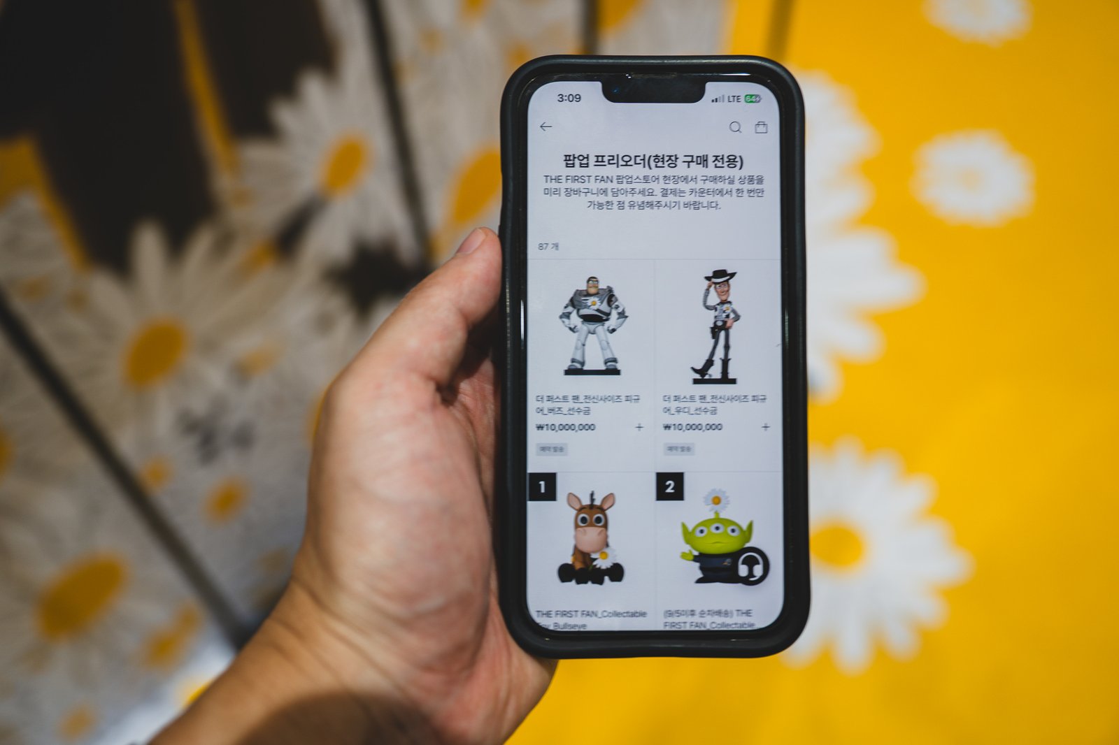 A screen inside the PLAY IN THE BOX app showing the pre-order listing for full-size Woody and Buzz figures, including a deposit line item