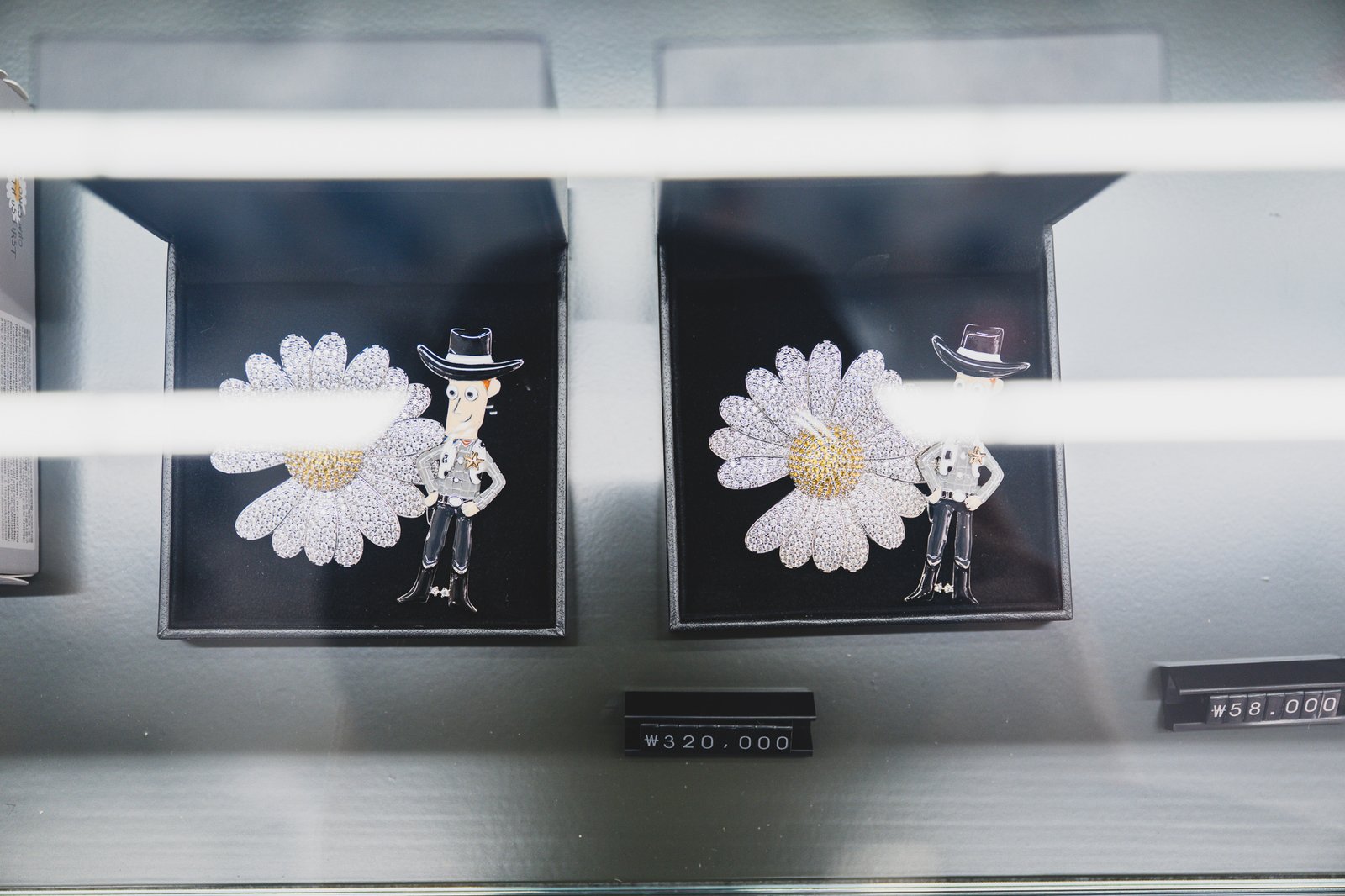 Two smaller daisy brooch pins on display with their price tags shown