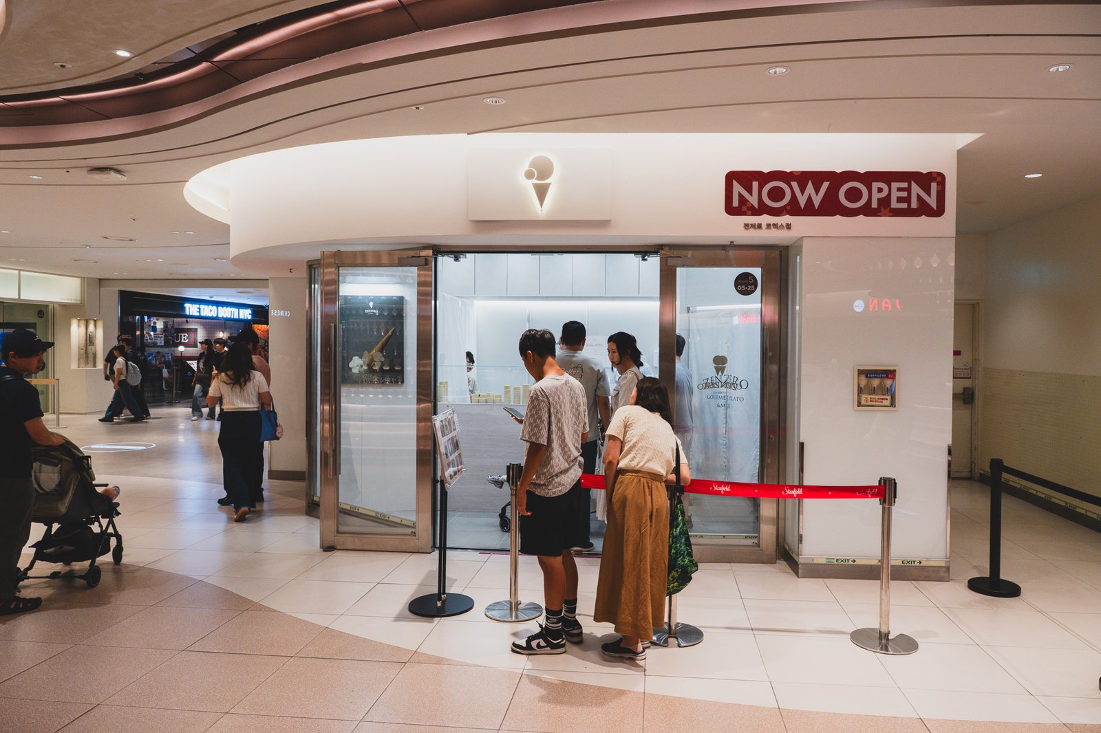 Storefront of the ZENZERO counter at Coex, a red "NOW OPEN" banner hanging above the ice-cream-cone logo sign, with a short line at the counter