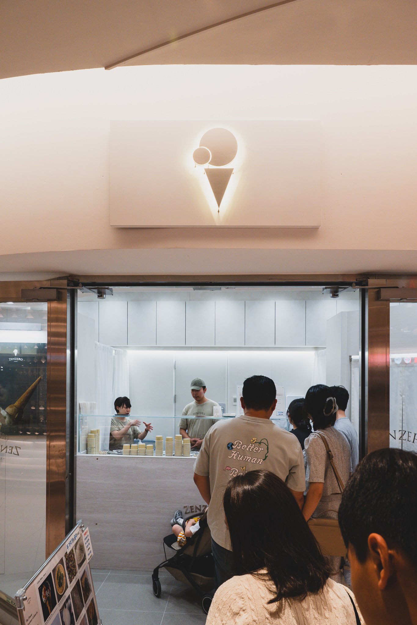 Interior view of the ZENZERO counter, staff scooping gelato behind a clean white-and-beige counter with no interior seating