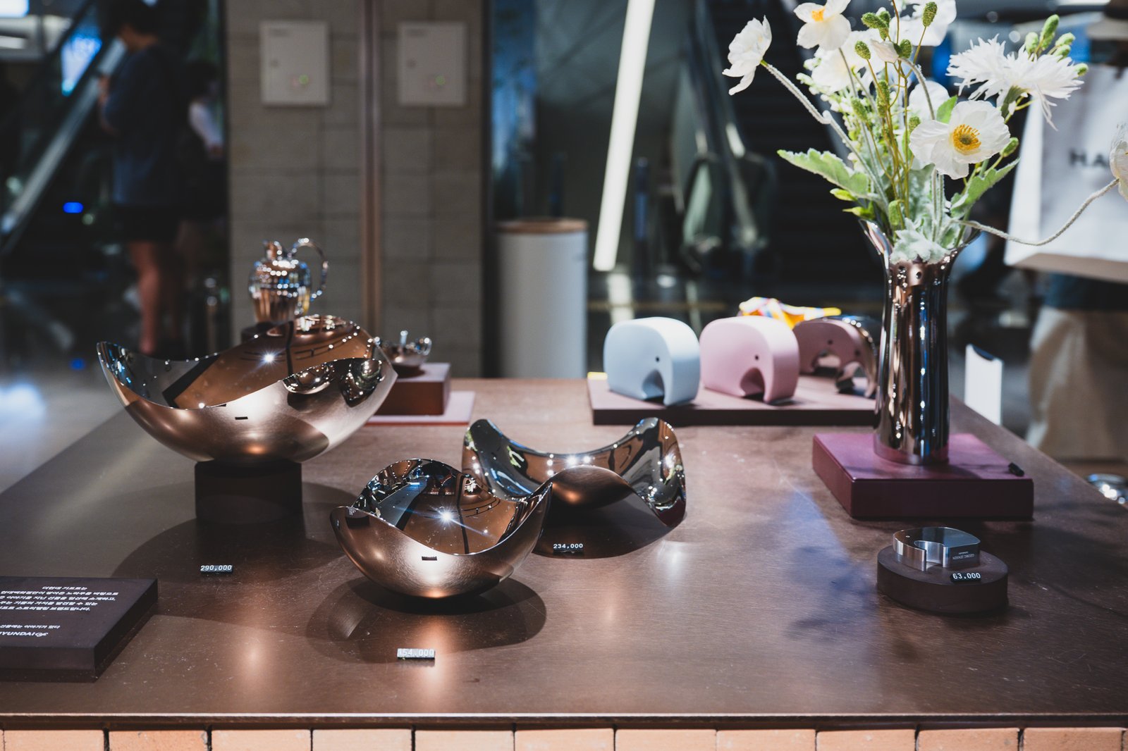 Mirror-polished stainless steel decorative bowls and a vase, individually price-tagged between 63,000 and 290,000 won