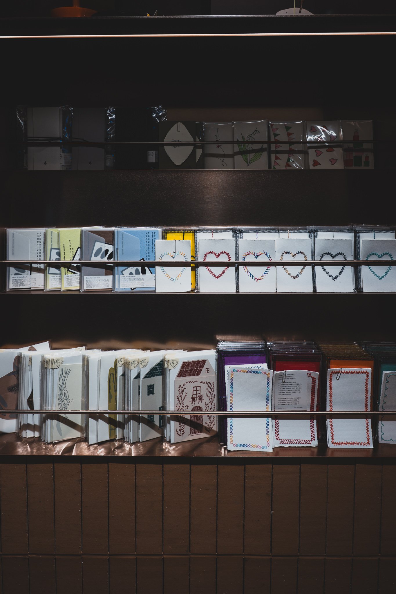 A wall display of greeting cards, letter paper, and small stationery items at The Hyundai Gift