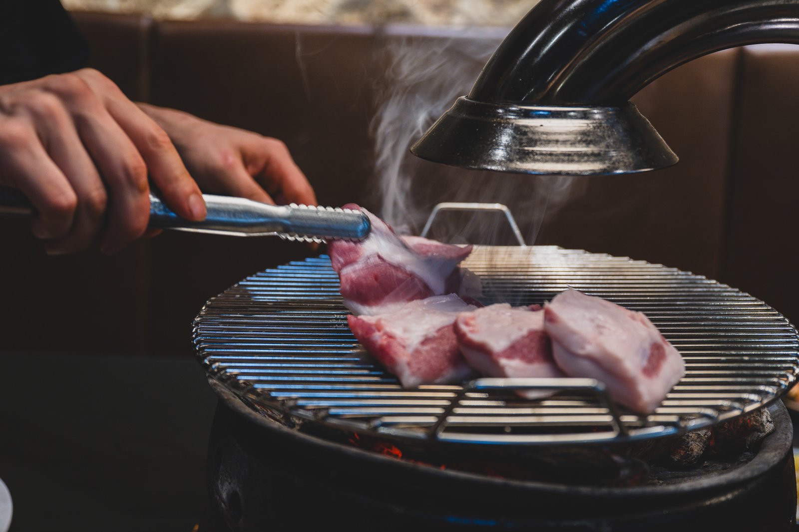 Thick-cut pork grilling directly over glowing red charcoal