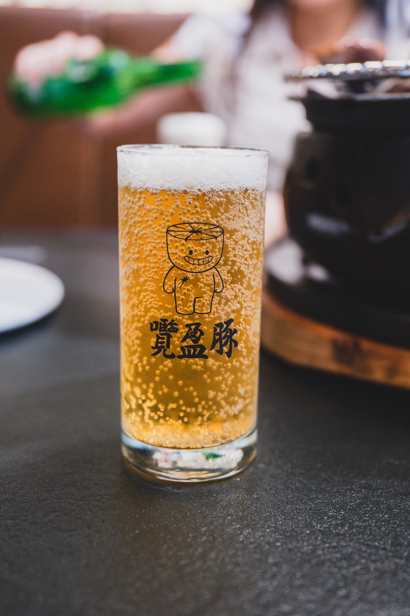 A draft beer glass printed with the restaurant's branded character illustration