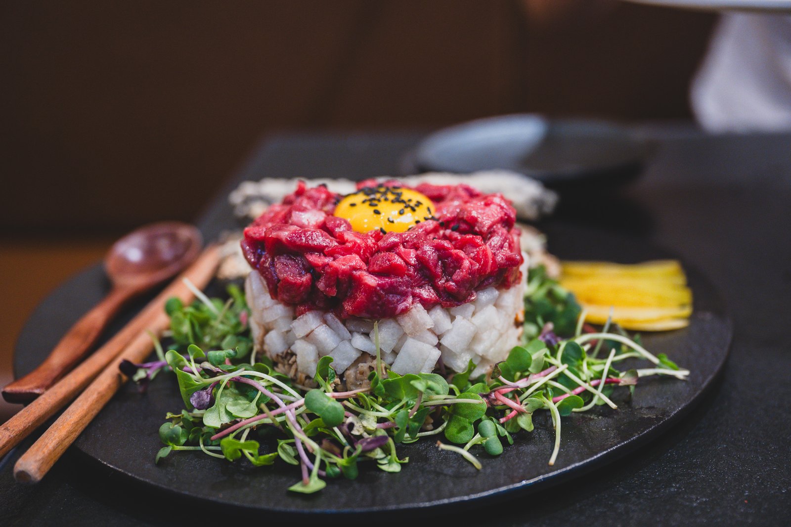 A plate of beef tartare (yukhoe) plated with egg yolk and julienned radish