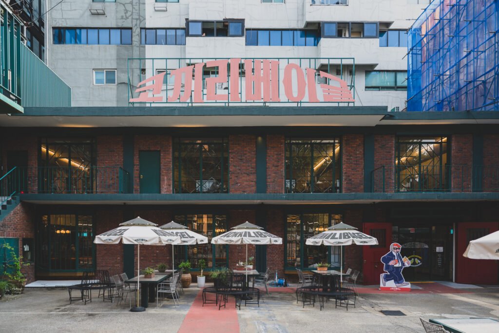 Storefront of Elephant Bagel Seongsu, a red-brick building with a large pink Elephant Bagel sign and an elephant-character statue by the entrance