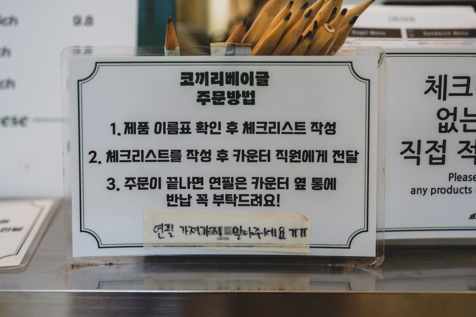A paper checklist order form with a pencil, used for marking bagel and sandwich selections