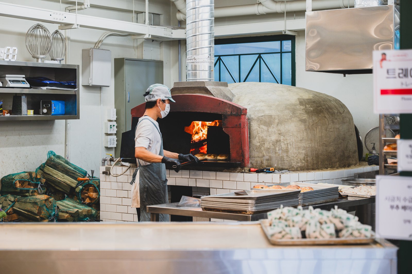 A staff member pulling a fresh bagel out of the wood-fired oven