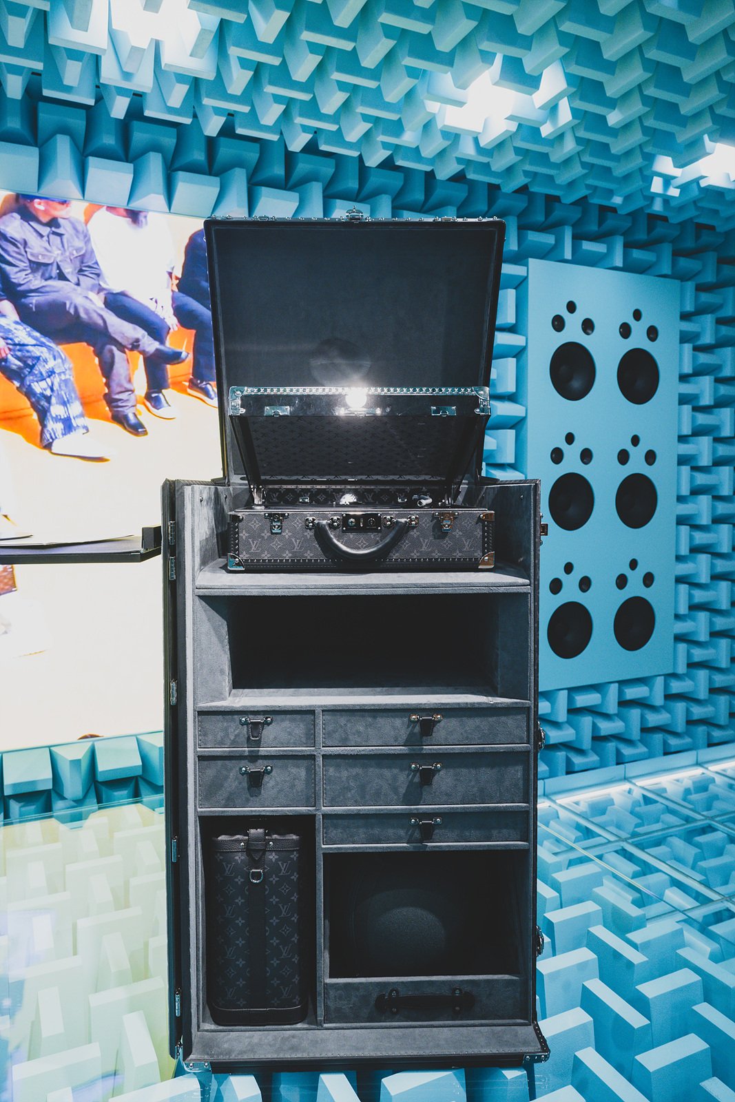 An open DJ trunk built into a rolling cabinet, set against an acoustic-foam-lined blue wall with built-in speakers