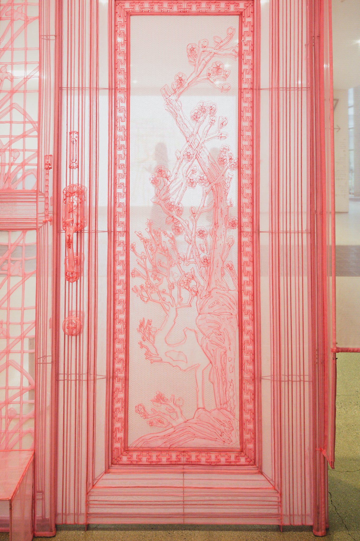 Bright pink translucent fabric hanok door with embroidered plum blossom branches visible through the fabric