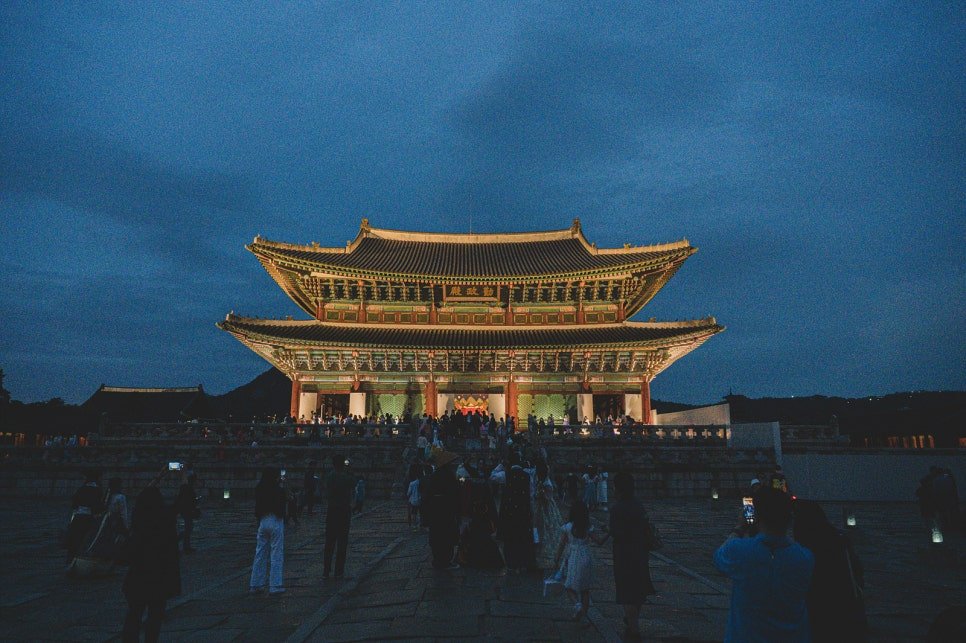 Geunjeongjeon, Gyeongbokgung's main throne hall, lit up at night with a crowd gathered in front