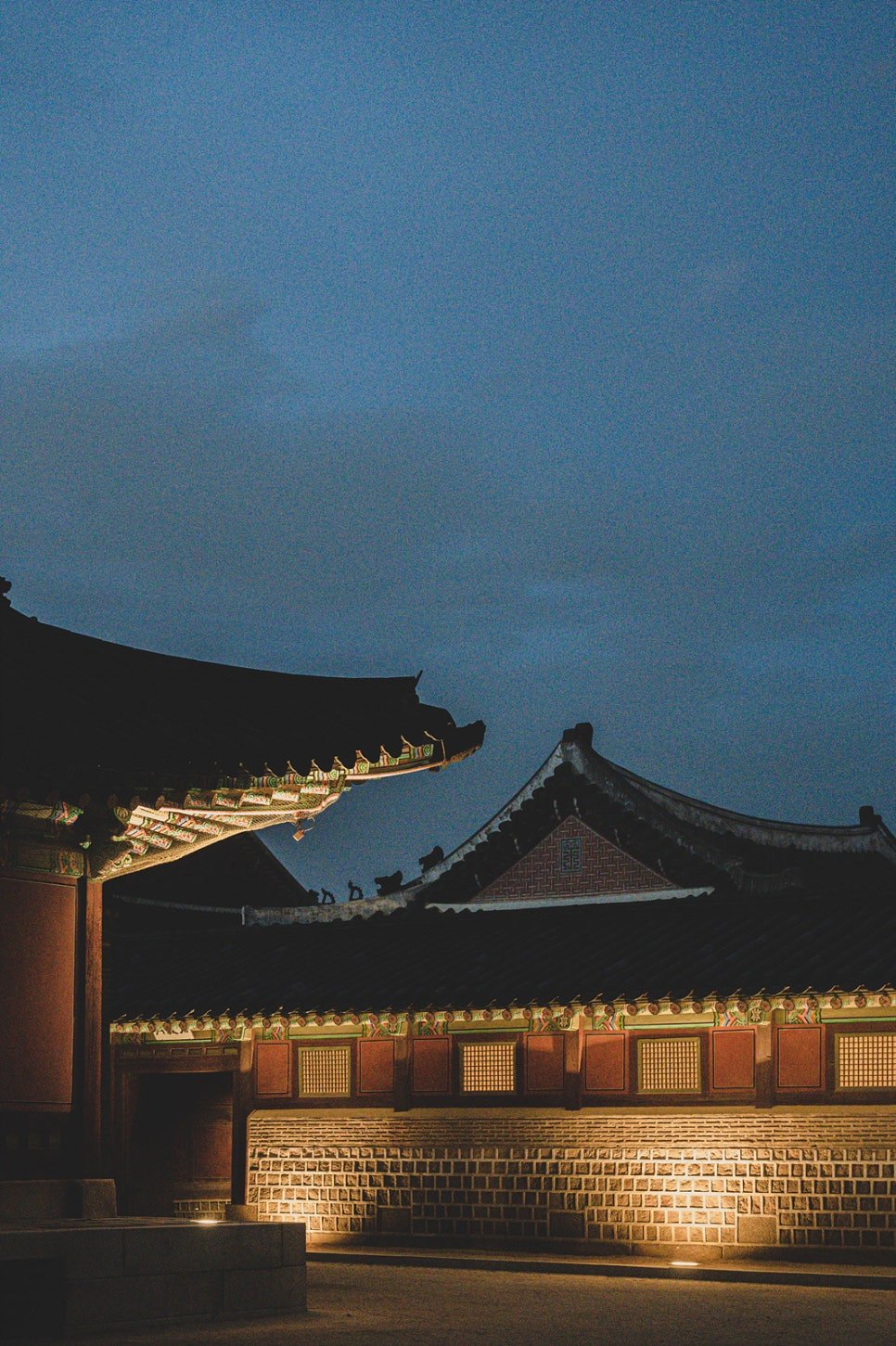 Close-up of illuminated dancheong (traditional painted eaves) on a side building at night