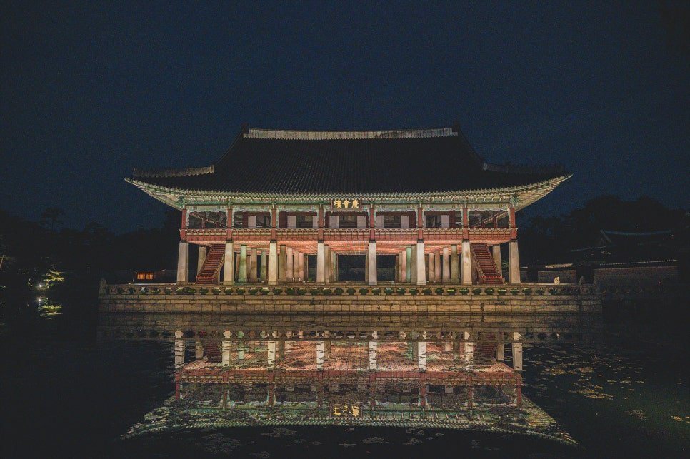 Gyeonghoeru pavilion at night, its reflection mirrored almost perfectly in the still pond in front of it