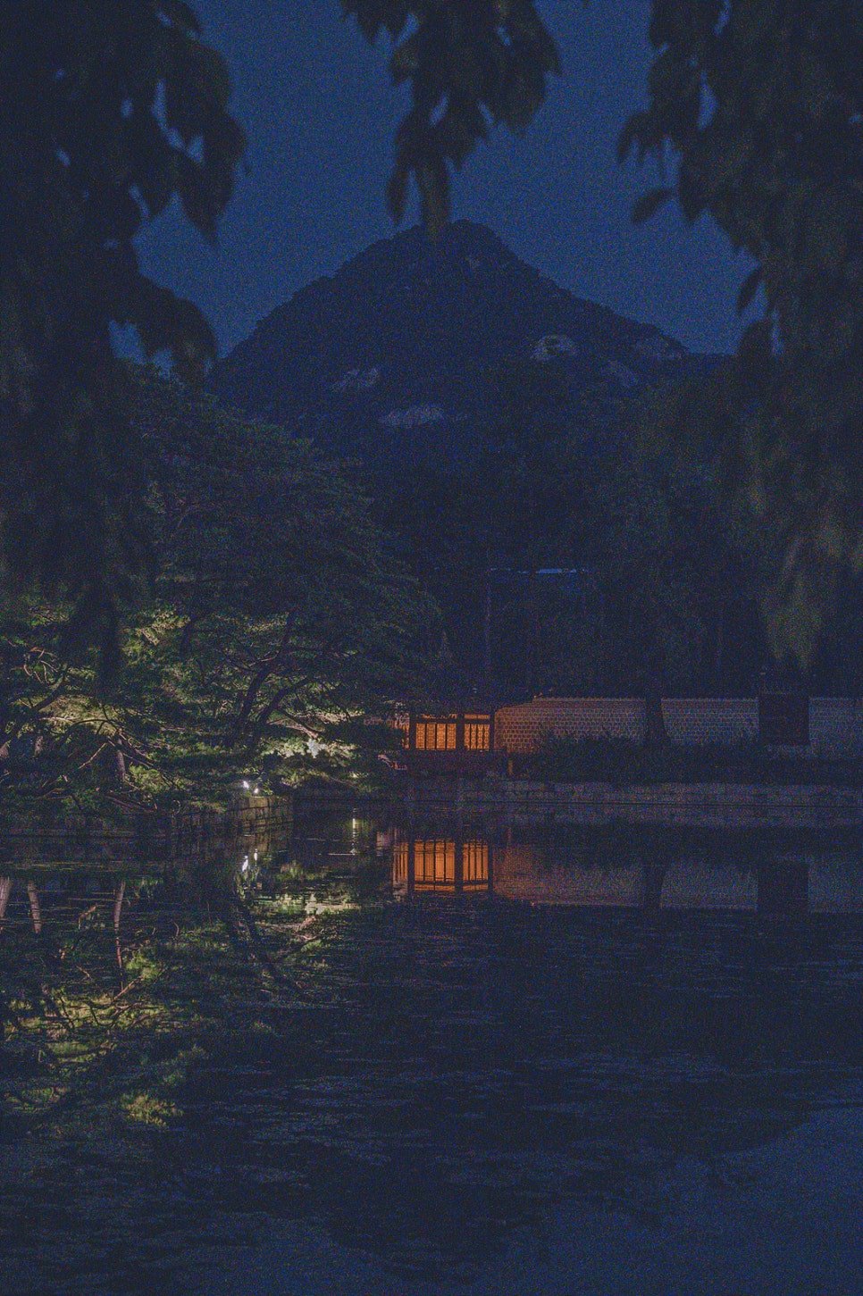 Bukhansan mountain visible in silhouette beyond the palace grounds at night