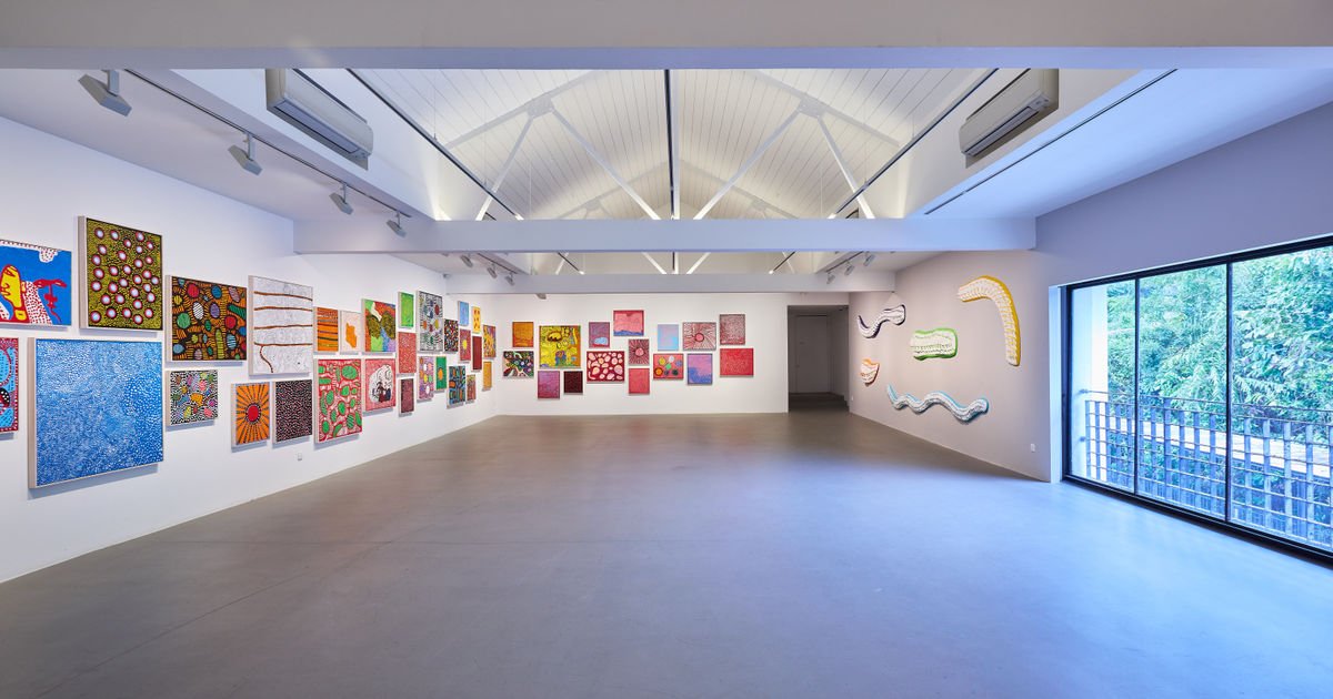 Installation view of Yayoi Kusama's "Every Day I Pray For Love" exhibition at Ota Fine Arts, paintings covered in her signature dot and net motifs with handwritten text