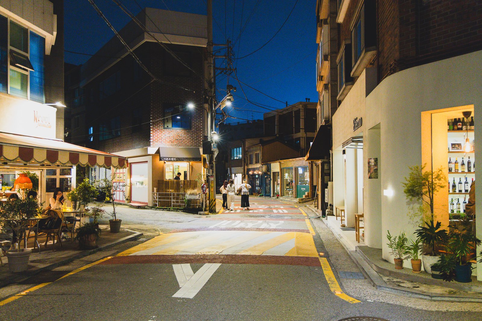 Seochon alley at night, low-rise buildings and outdoor seating at neighboring shops