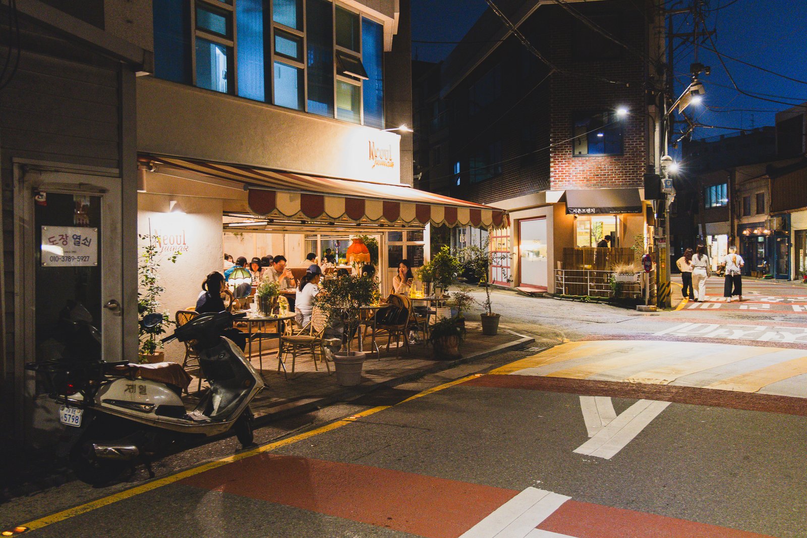 Another view of the quiet Seochon alley at night, with warm lighting from nearby cafes and bars
