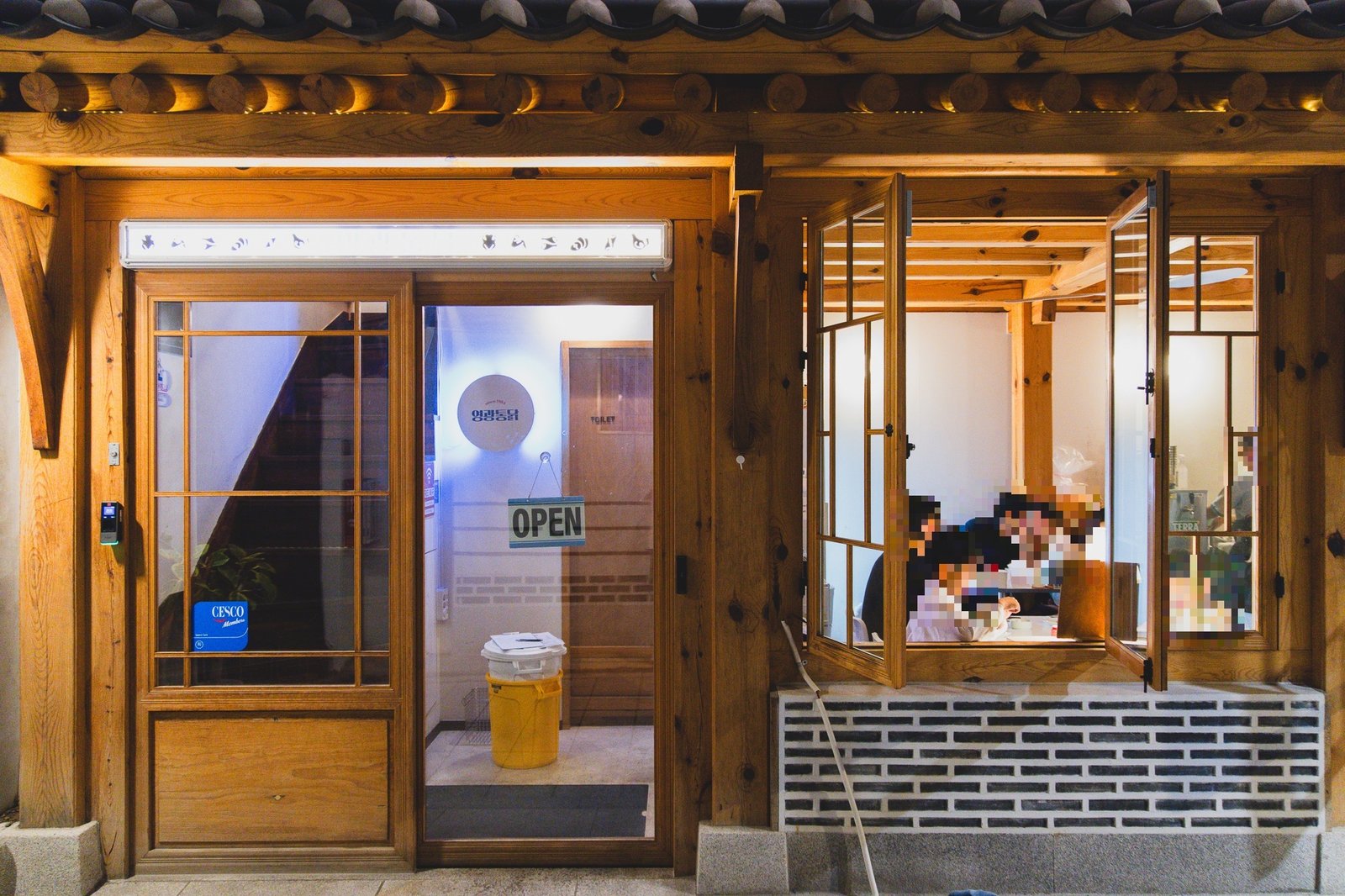 Open windows at night with diners visible inside, OPEN sign hanging on the door