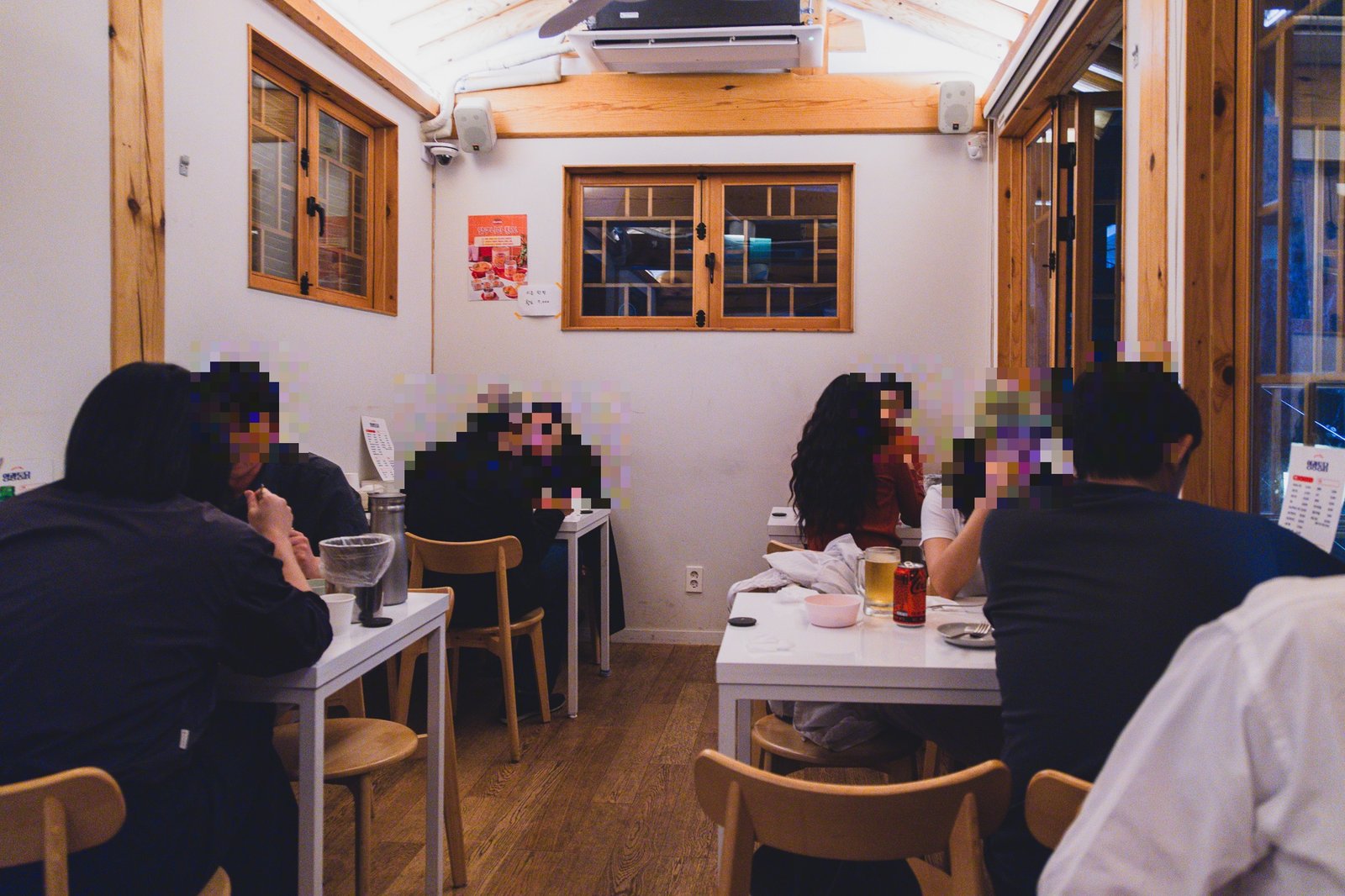 Interior seating area with white tables and wooden chairs, diners eating