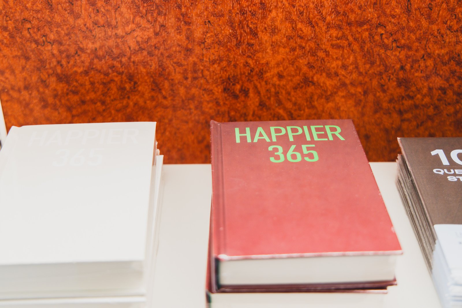 The "HAPPIER 365" diary, a red hardcover daily journal