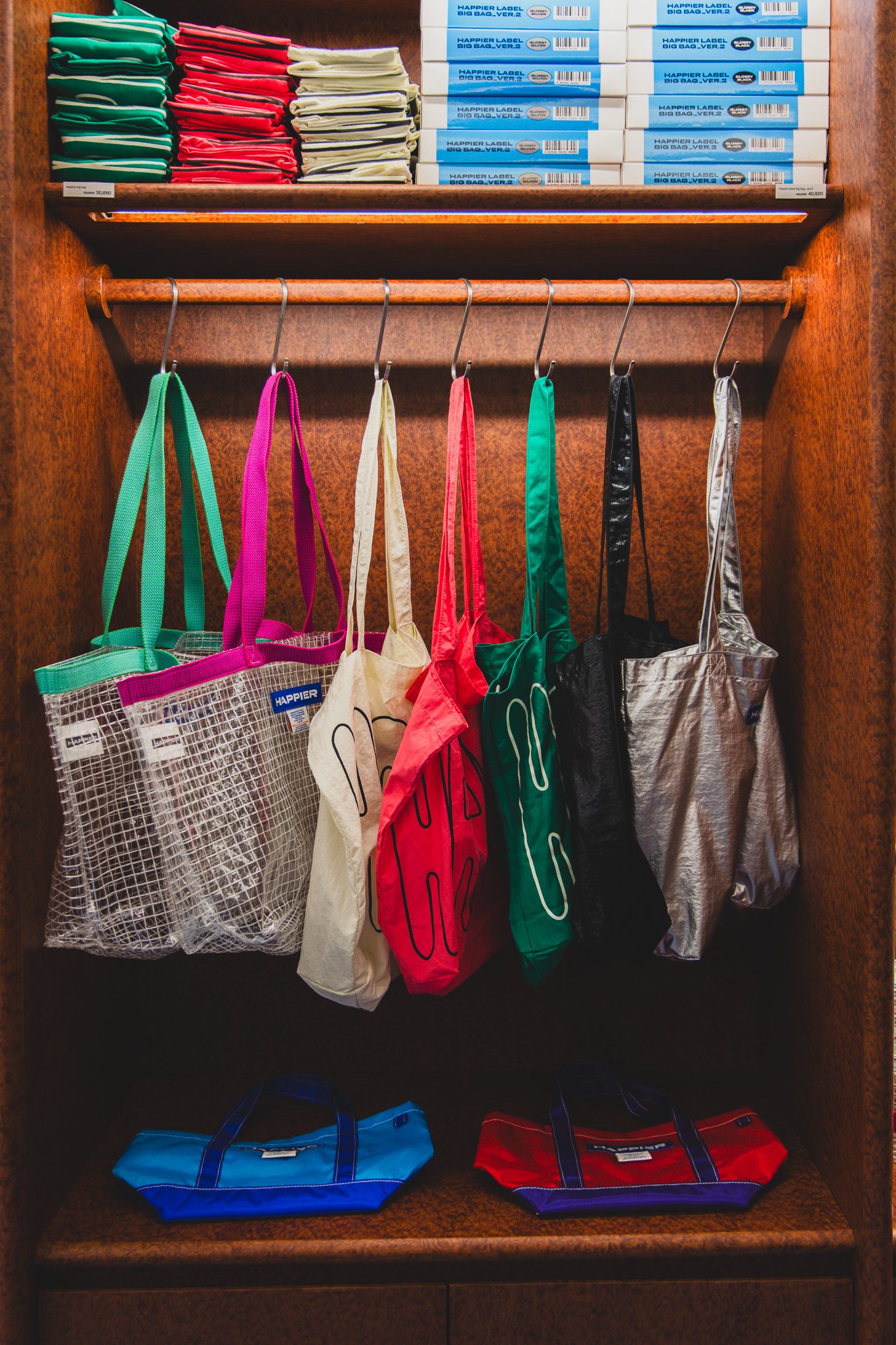 Colorful tote bags and larger canvas bags hanging on a rack
