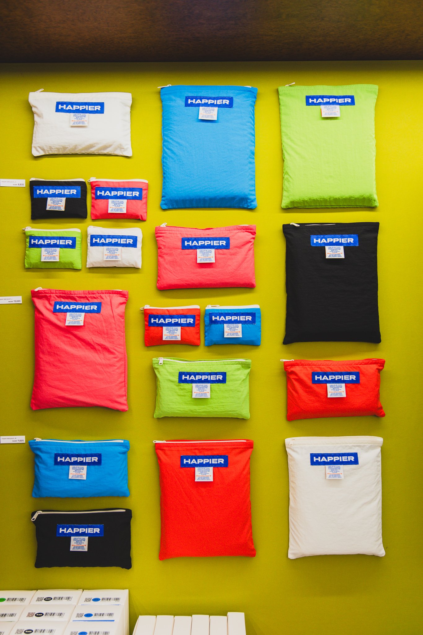 A wall of colorful HAPPIER pouches in multiple sizes and colors