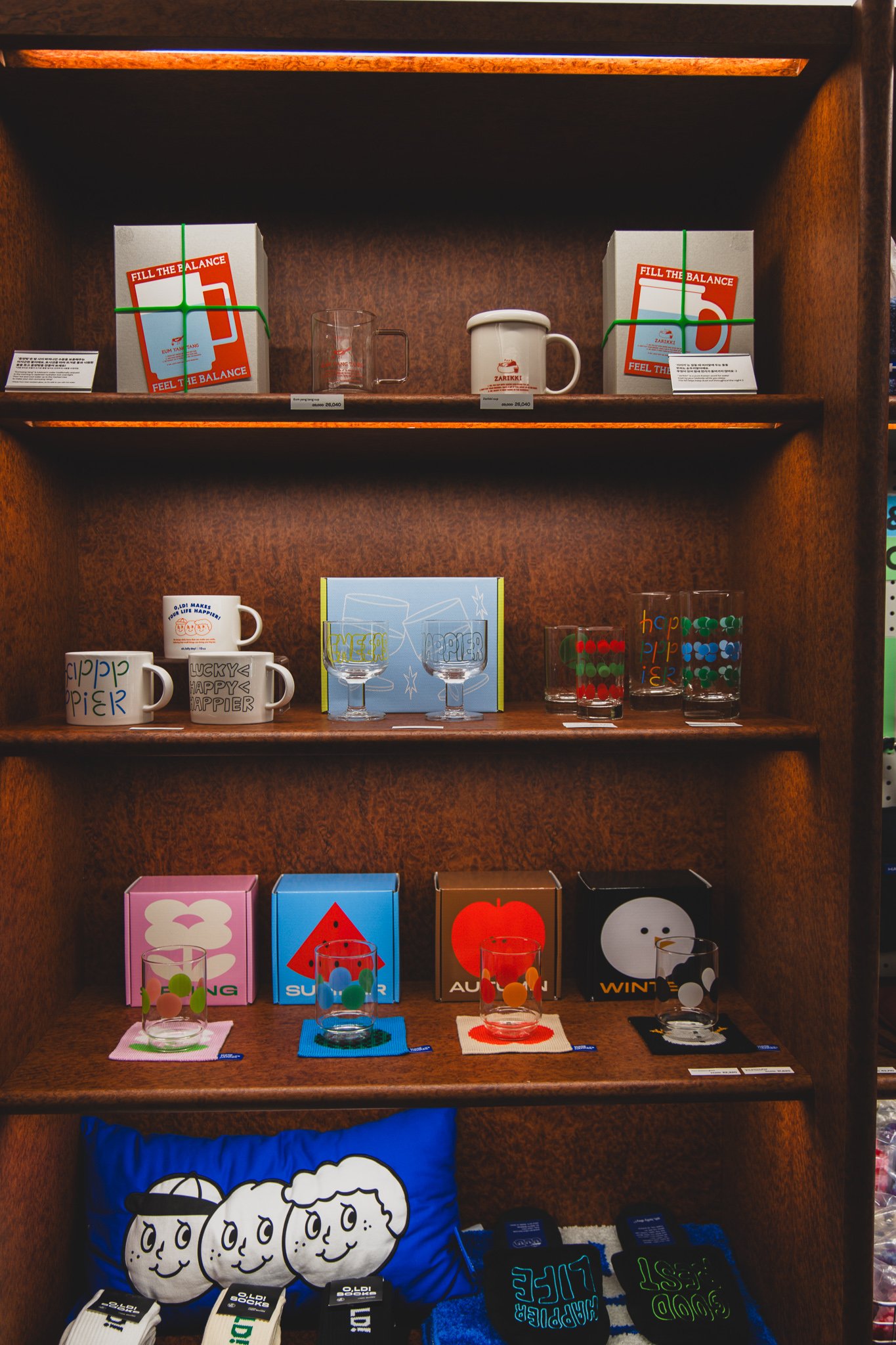 HAPPIER-branded mugs, glasses, and a seasonal glassware set with a handwritten-style logo