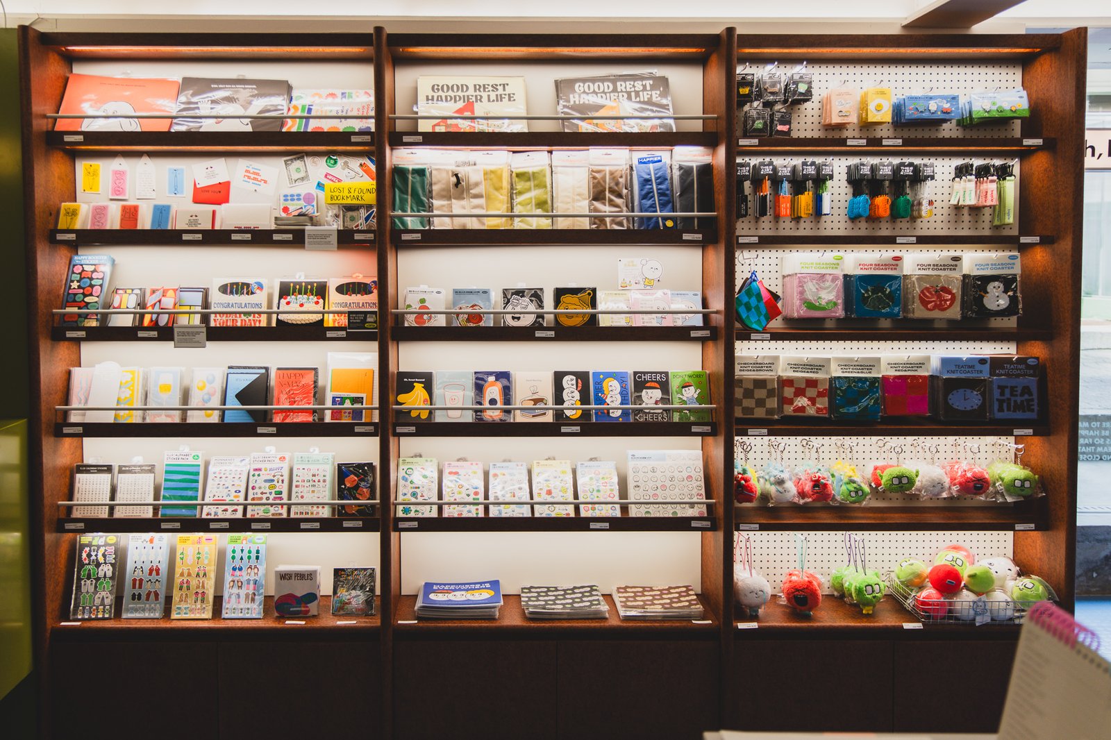 A wall of cards, stickers, knit coasters, and character keyrings near the checkout counter