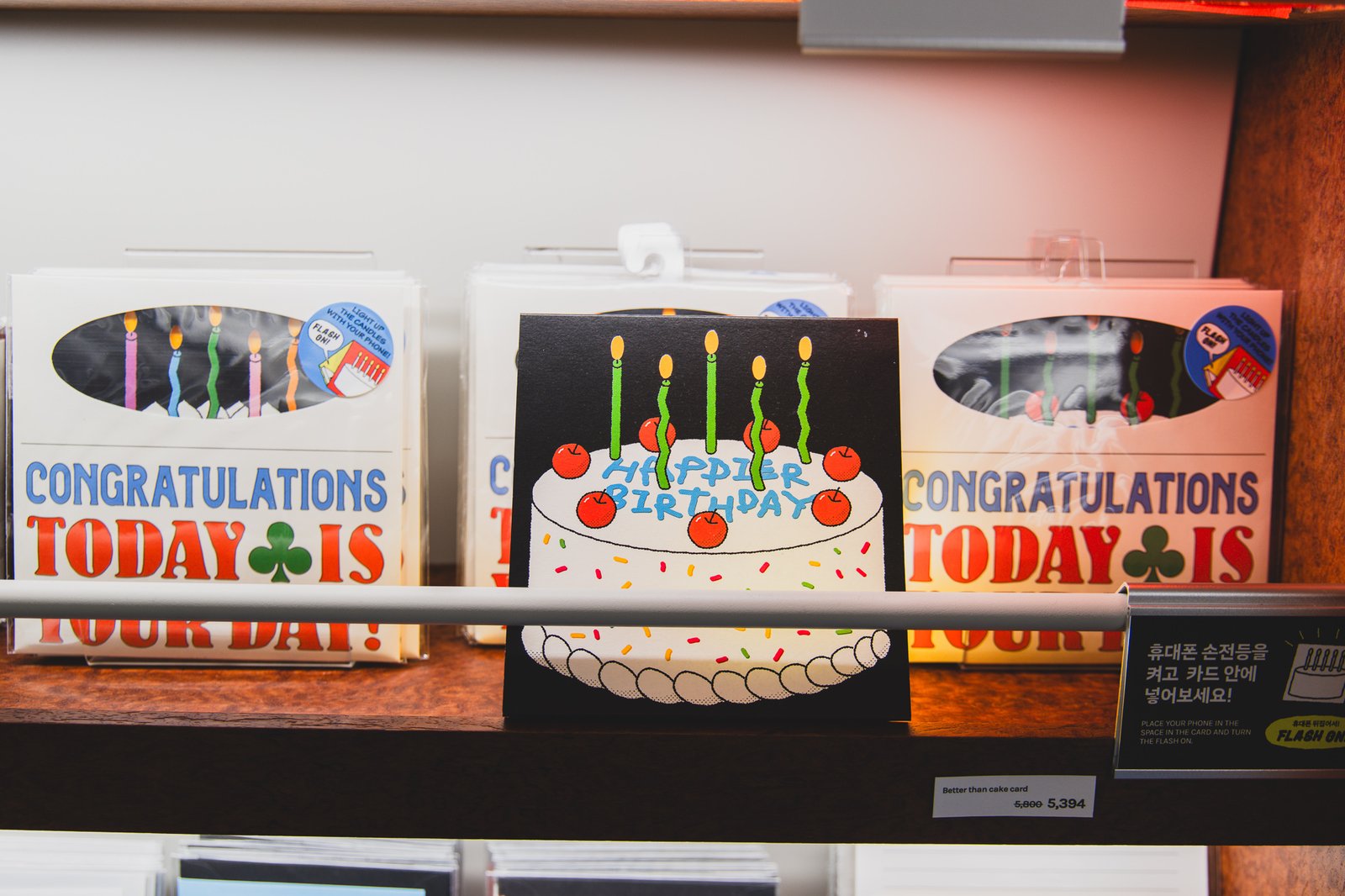 A "HAPPIER BIRTHDAY" flash card, designed so shining a phone flashlight through it lights up a printed candle