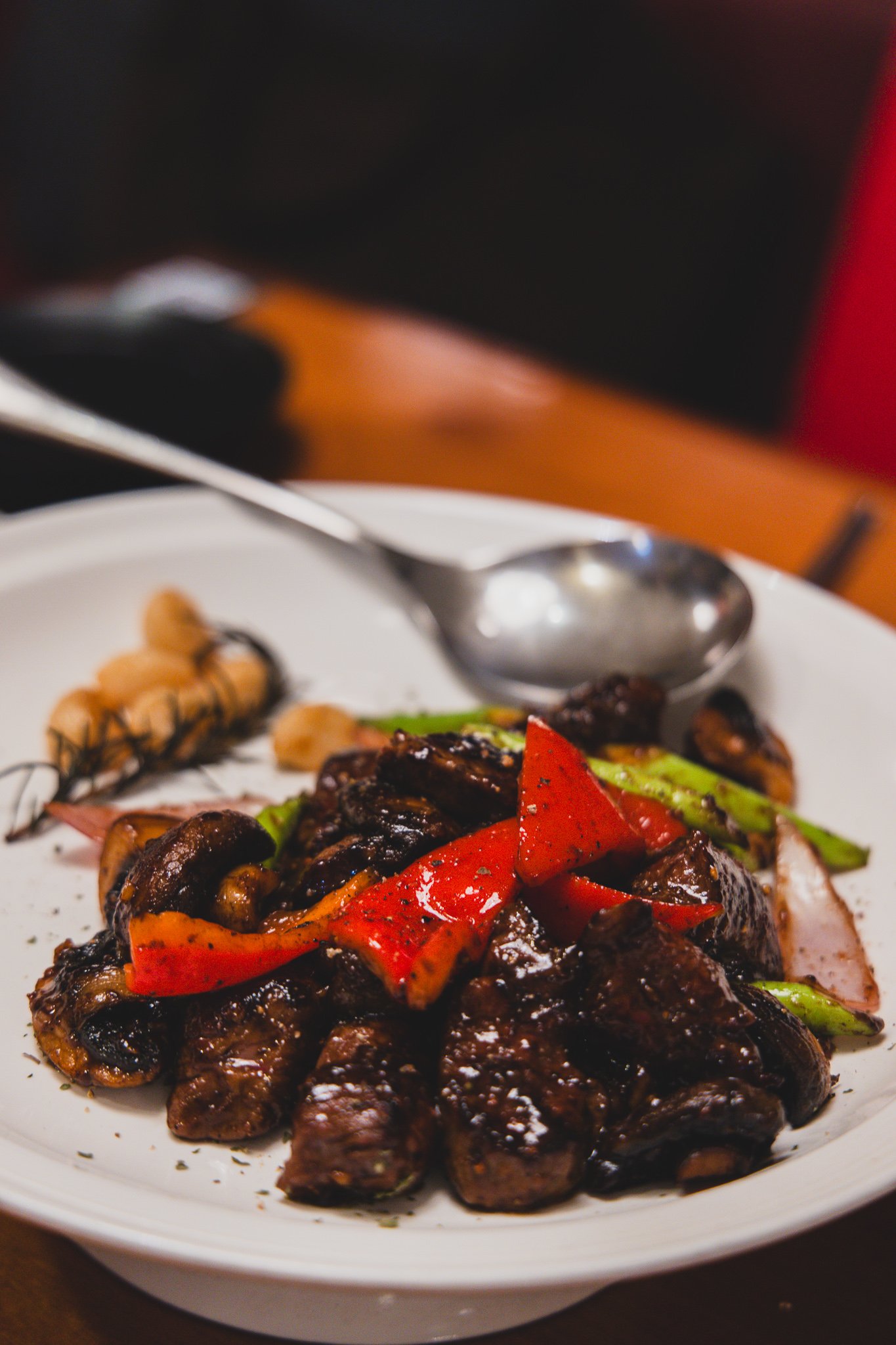 A finished plate of black pepper tenderloin with charred beef, red bell pepper, asparagus, and mushroom, freshly peppered and ready to eat