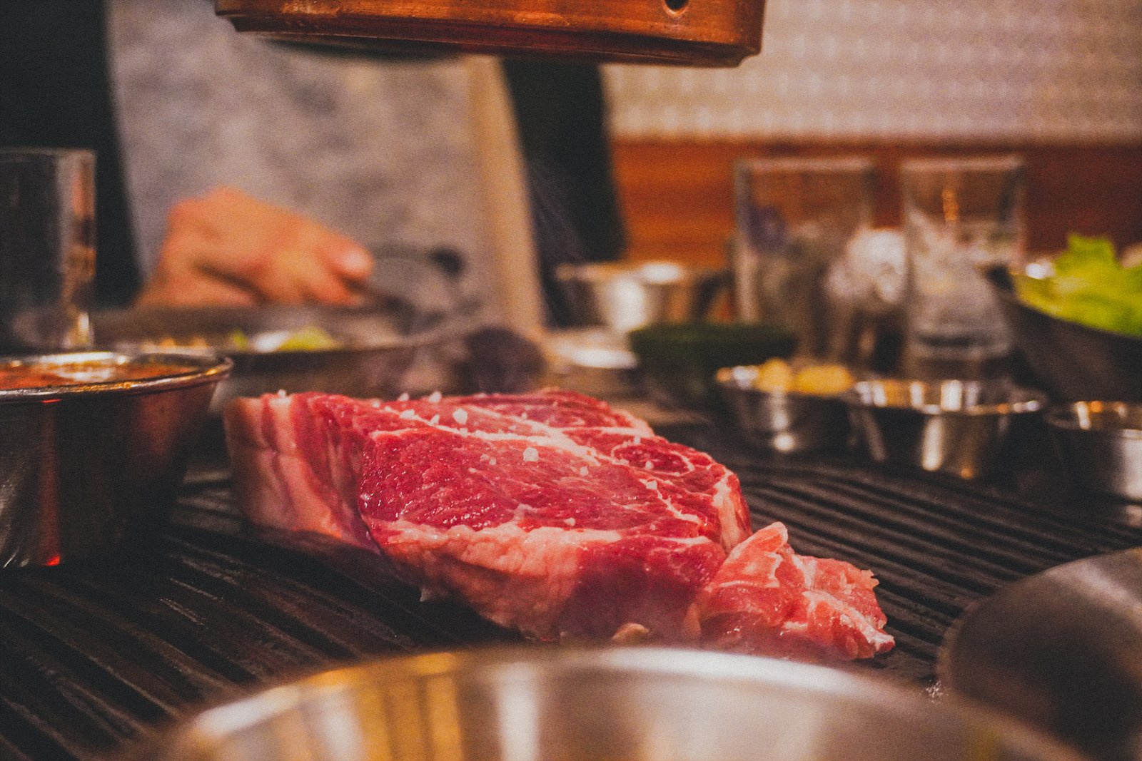 a single thick, marbled cut of pork grilling whole on the charcoal grate
