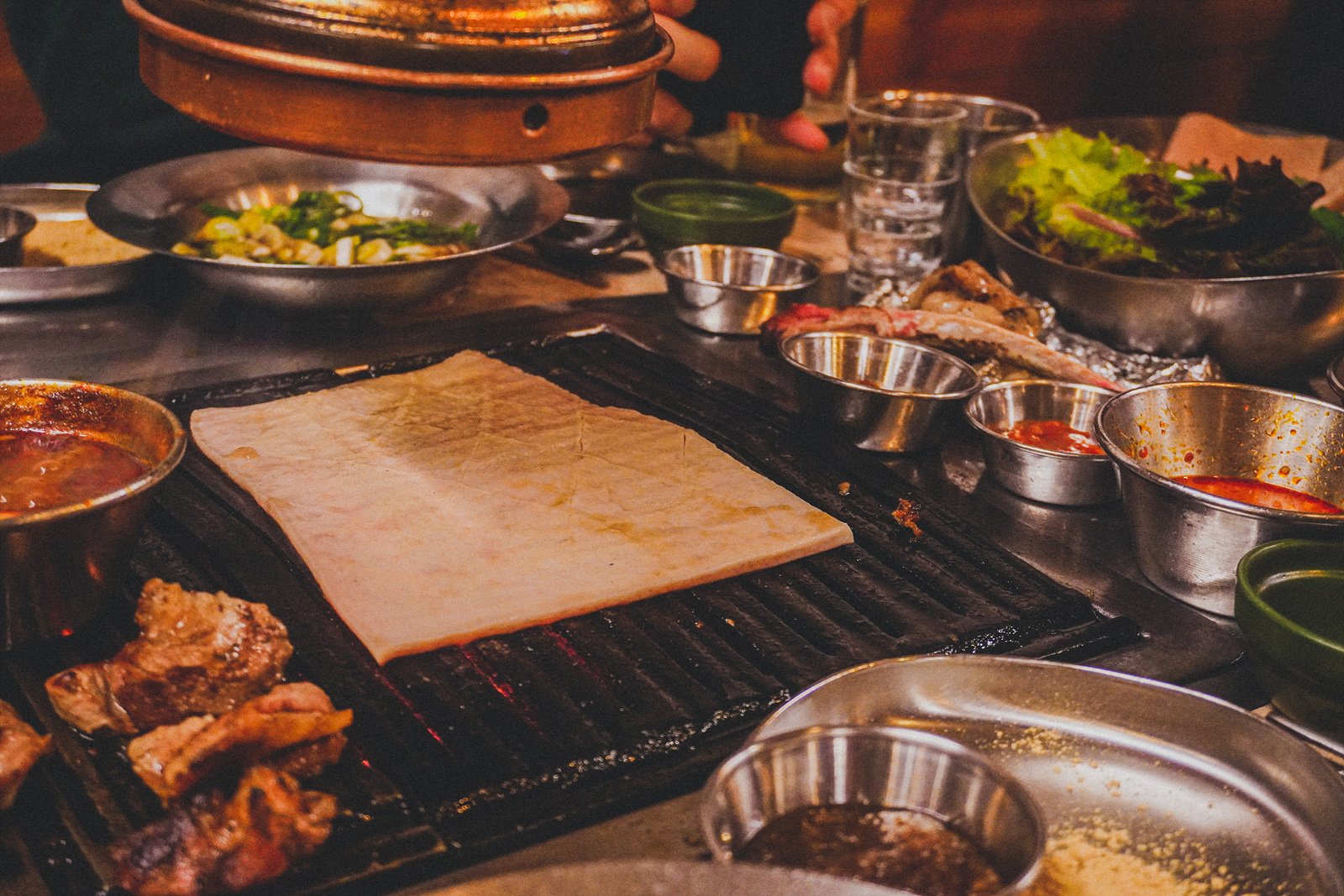 a raw, pale slab of pork skin laid flat on the grill