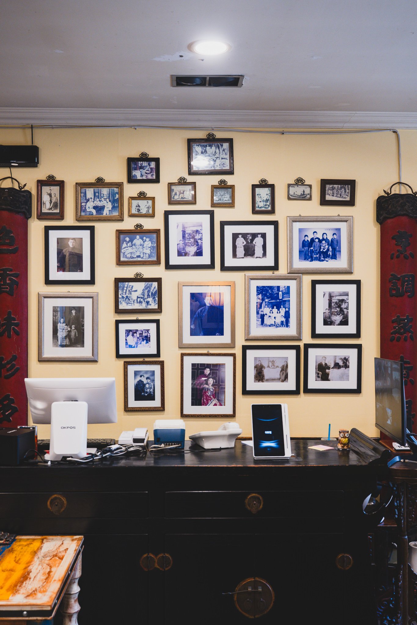 Wall behind the counter completely covered with black-and-white and sepia family photographs spanning several generations