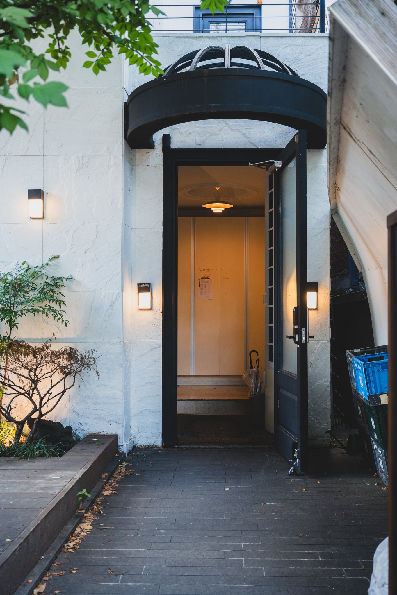 Arched black-framed entrance canopy with soft light spilling out