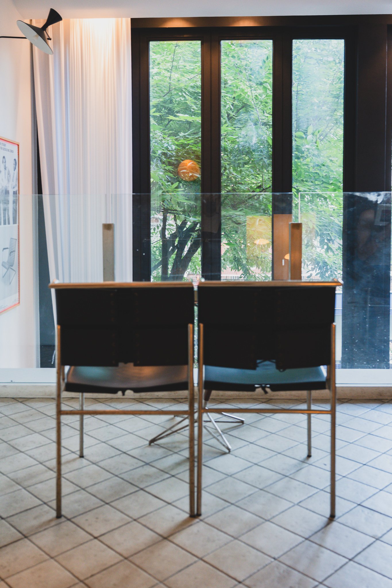 Leather chair from behind, with an orange Akari lamp visible through the window among tree branches